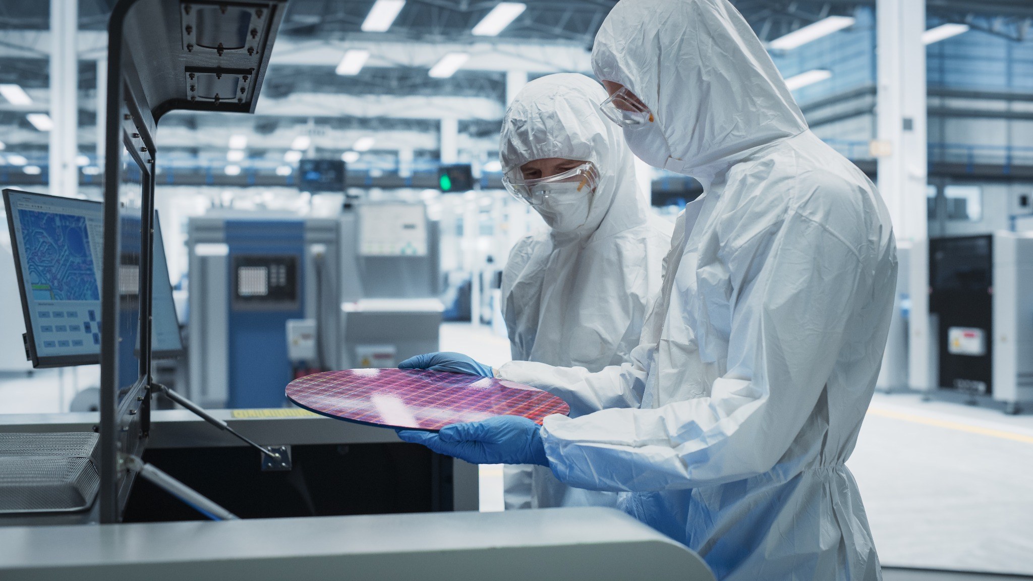Semiconductor technicians inspecting a silicon wafer in a cleanroom environment